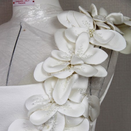 Détail des fleurs en tissu et perles faites main sur la robe de mariée longue au sol