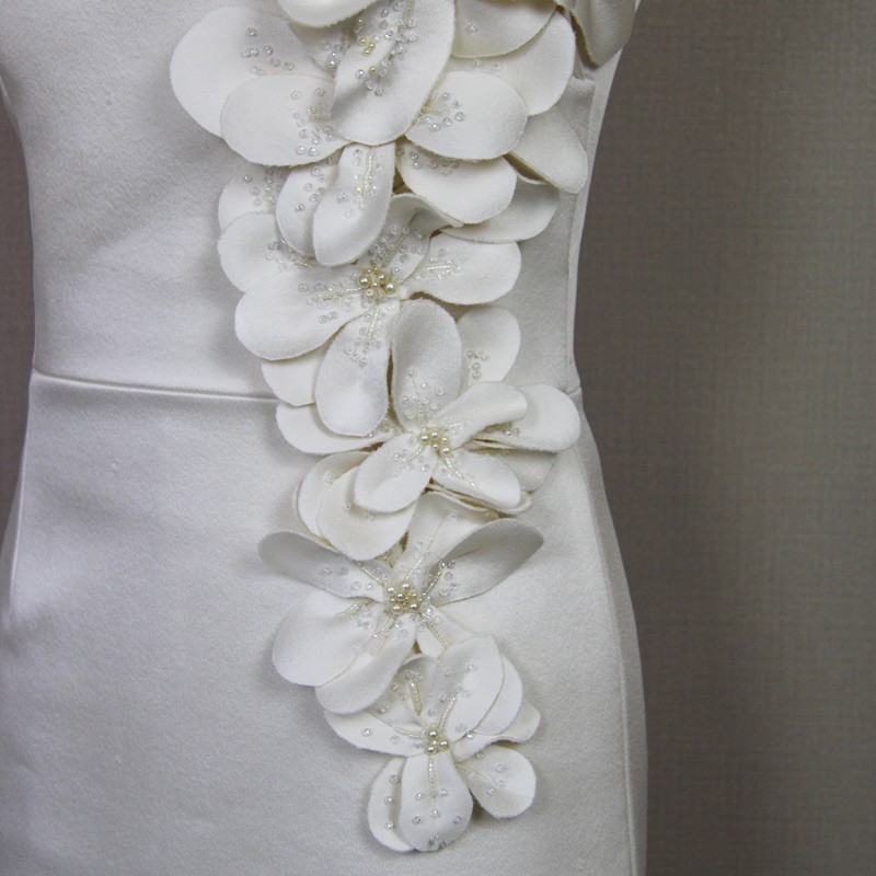 Détail des fleurs en tissu et perles faites main sur la robe de mariée