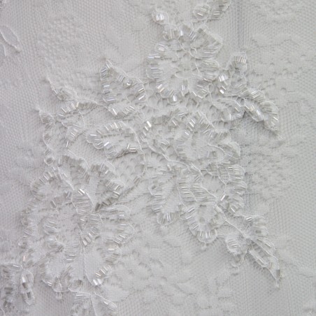Close up on the lace with intricate hand embellishments on a minimalist bridal gown.