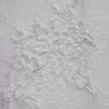 Close up on the lace with intricate hand embellishments on a minimalist bridal gown.