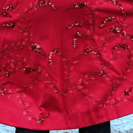 Gros plan sur la broderie florale artisanale sur le dos du manteau rouge en laine.