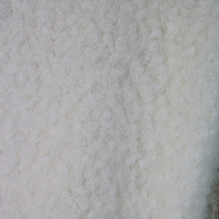 Détail de la texture bouclée ivoire du manteau fait main.