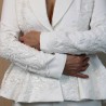 Gros plan sur les broderies couture d’un tailleur de mariée fait main