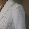 Gros plan sur les broderies couture d’un tailleur de mariée fait main