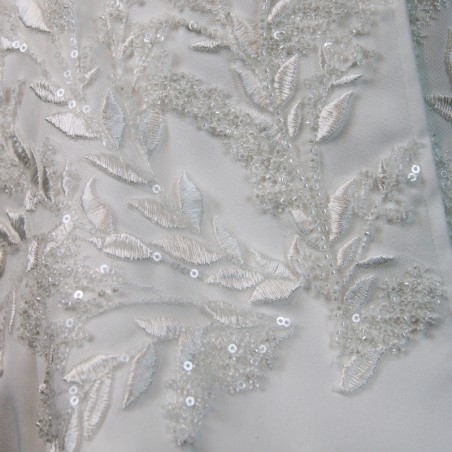 Gros plan sur les broderies couture d’un tailleur de mariée fait main