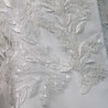 Gros plan sur les broderies couture d’un tailleur de mariée fait main