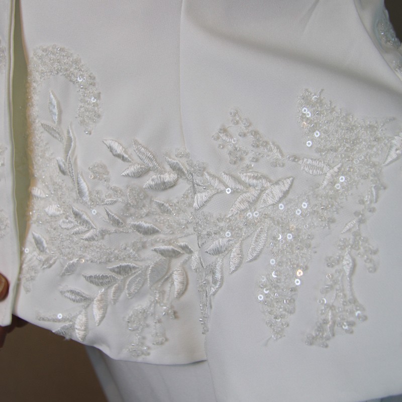 Gros plan sur les broderies couture d’un tailleur de mariée fait main