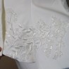 Gros plan sur les broderies couture d’un tailleur de mariée fait main