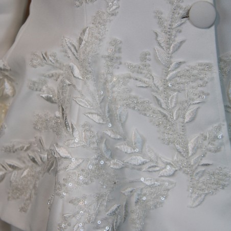 Gros plan sur les broderies couture d’un tailleur de mariée fait main