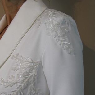 Gros plan sur les broderies couture d’un blazer de mariée fait main