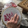 Gros plan sur une broderie florale en cours de réalisation sur le corsage d’une robe de mariée
