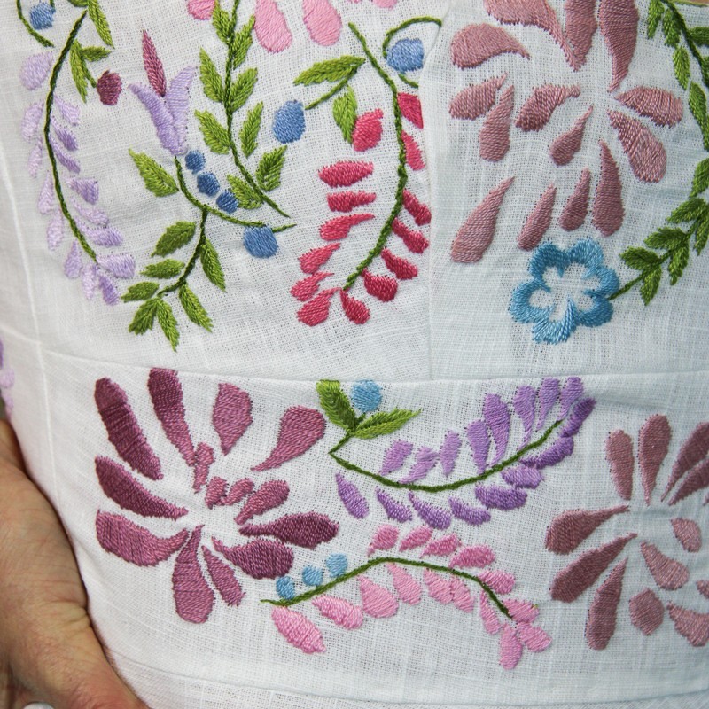 Détail des broderies délicates faites à la main sur le corsage d’une robe de mariée éco-responsable.
