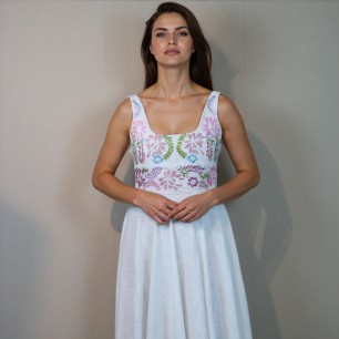 A bride wearing a floor length linen hand embroidered wedding dress standing gracefully