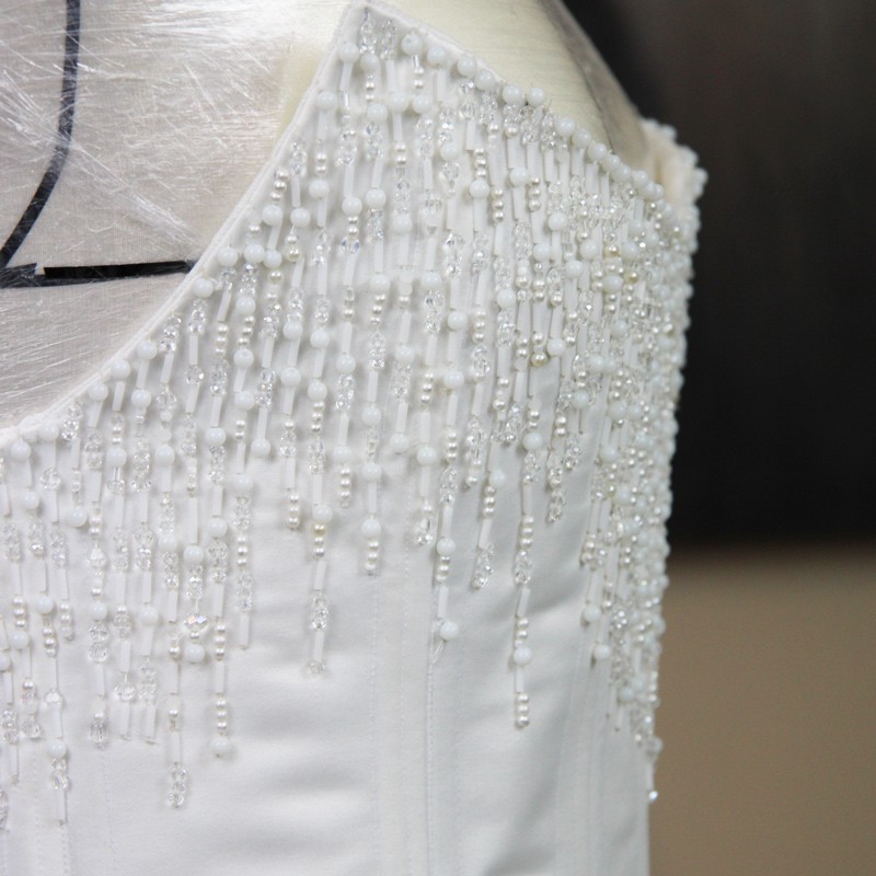 Gros plan du ornement de pierres scintillantes sur corset de mariée, fait sur mesure