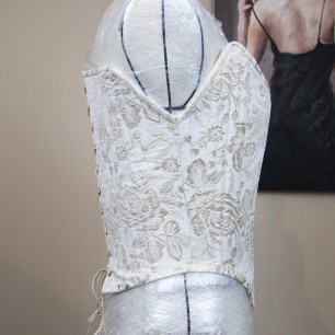 Vue de côte d’un corset fait main présenté sur un mannequin.