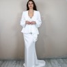 White bridal ensemble with asymmetrical pleated peplum blazer, belted waist, and floor-length skirt with train.