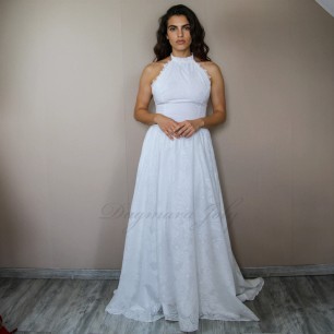 Modele portant une robe de mariée longue en coton, à col licou et traîne fluide, debout dans un chambre