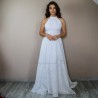 Modele portant une robe de mariée longue en coton, à col licou et traîne fluide, debout dans un chambre