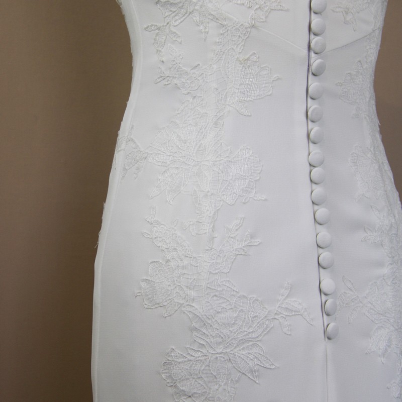 Détail de dentelle brodée main sur une robe de mariée moderne en crêpe