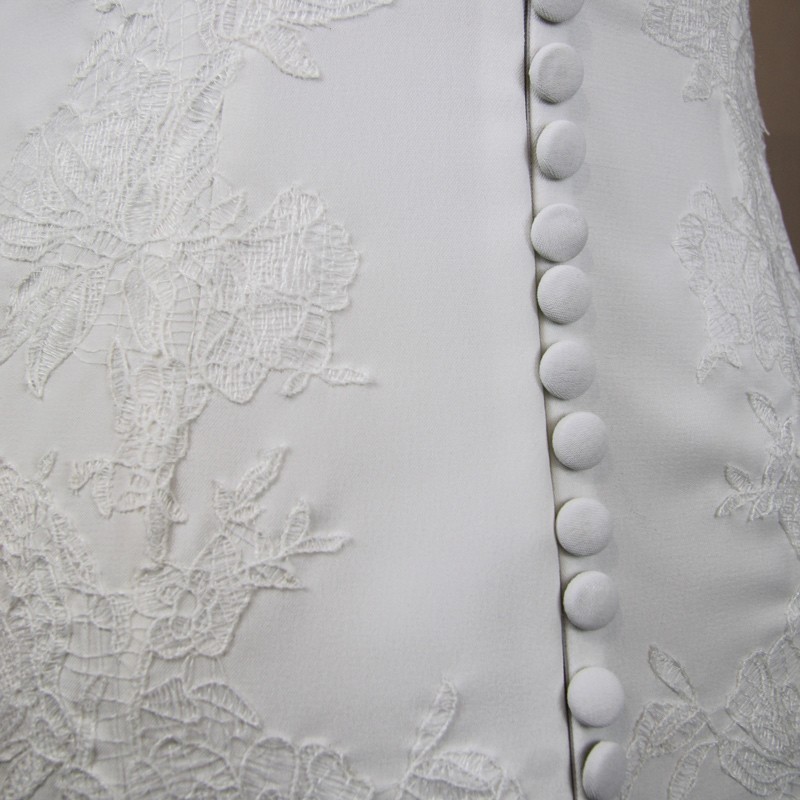 Détail des boutons décoratifs au dos d’une robe de mariée élégante en crêpe