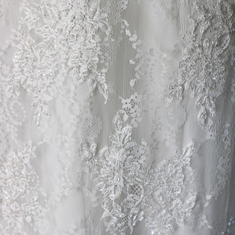 Zoom sur les détails de la robe de mariée en dentelle chantilly ornée à la main