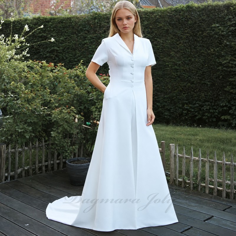 Bride wearing two-piece wedding dress with long flowing train, standing in natural light