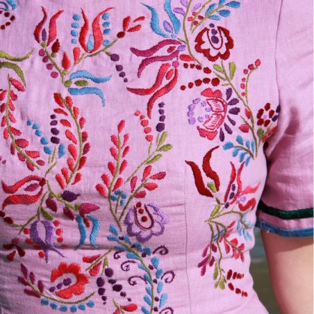 Close-up of hand-embroidered floral design on violet linen fabric