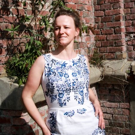 Close-up of hand-embroidered details on white linen sleeveless pencil dress featuring elegant open-back design