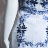 Detailed shot of hand-embroidered motifs on a back of white linen sleeveless dress,