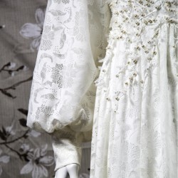 Gros plan sur la dentelle florale du devant de la robe, finement brodée à la main avec des perles nacrées