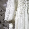 Gros plan sur la dentelle florale du devant de la robe, finement brodée à la main avec des perles nacrées