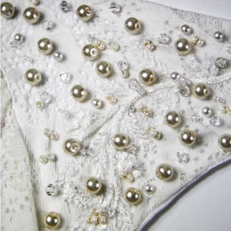 Gros plan sur la dentelle florale du devant de la robe, finement brodée à la main avec des perles nacrées