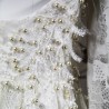 Gros plan sur la dentelle florale du devant de la robe, finement brodée à la main avec des perles nacrées