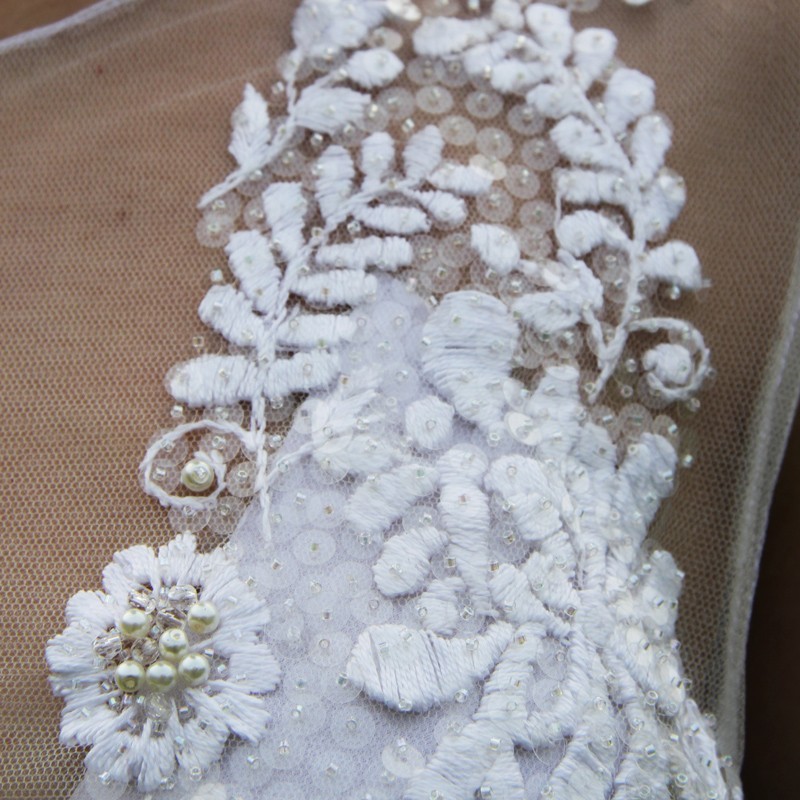 Gros plan sur les délicates broderie à la main sur le tulle.