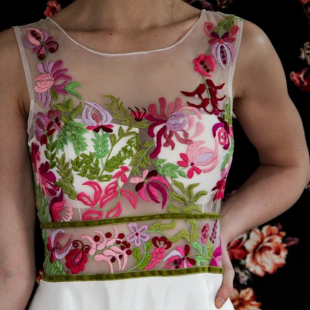 Details of exquisite colorful hand embroidery on white sleeveless bridal or evening dress