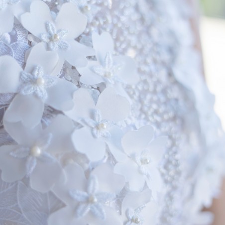 Zoom sur les perles, fleurs découpées à la main et sequins sur la robe de mariée en dentelle.