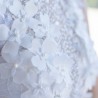 Close-up of hand-sewn pearls and floral appliqués on lace fabric of wedding dress, showcasing artisanal craftsmanship.