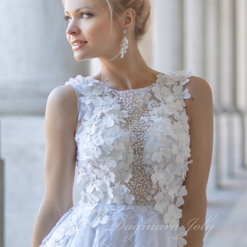 Close-up of hand-sewn pearls and floral appliqués on lace fabric of wedding dress, showcasing artisanal craftsmanship.