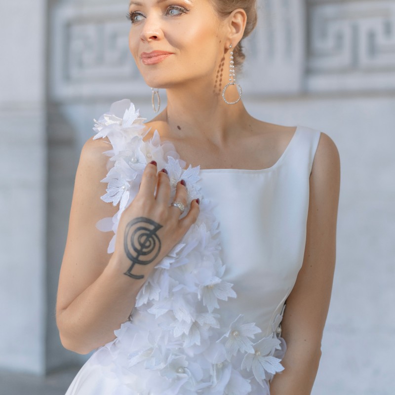 Modèle portant une robe de mariée courte, ornée de fleurs, vue de face, confectionnée sur mesure en France.