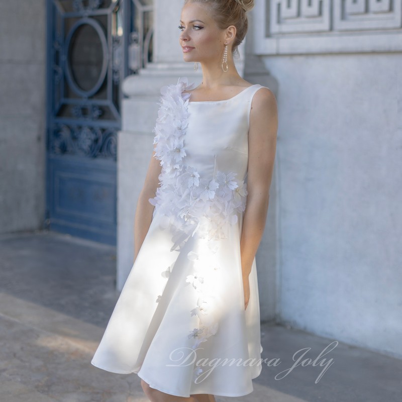 Model wearing a white short sleeveless wedding dress with floral embellishments, front view, custom-made in France.