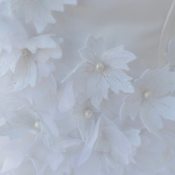 Zoom sur les détails floraux et la texture légère de la robe de mariée courte sur mesure, fabriquée en France.