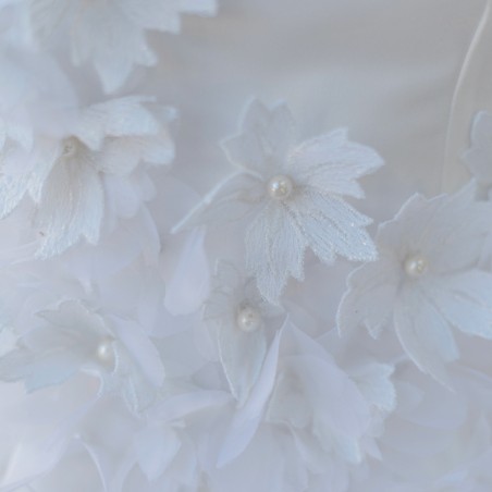 Zoom sur les détails floraux et la texture légère de la robe de mariée courte sur mesure, fabriquée en France.