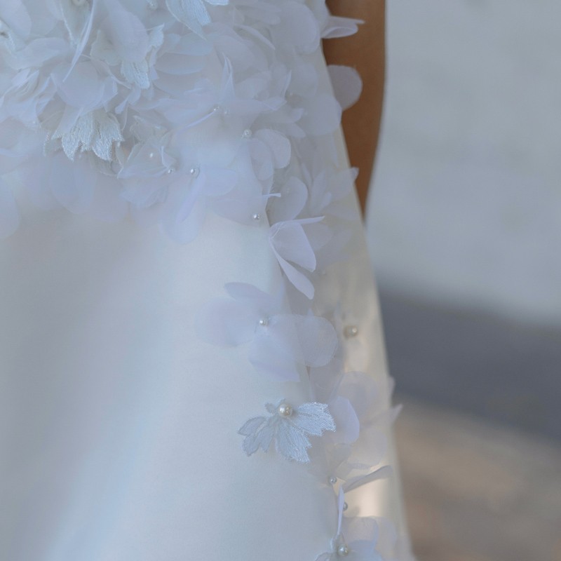 Close-up of floral embellishments on a white short wedding dress, handcrafted lace and embroidery.