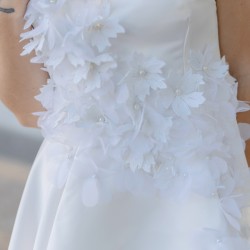 Zoom sur les détails floraux et la texture légère de la robe de mariée courte sur mesure, fabriquée en France.