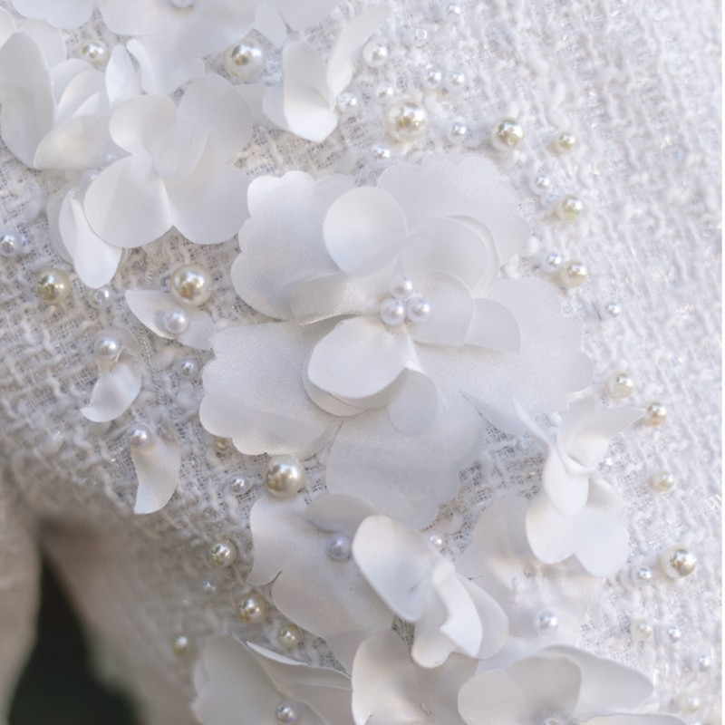 Close-up of the luxurious tweed fabric of a short wedding dress, highlighting texture and detail.