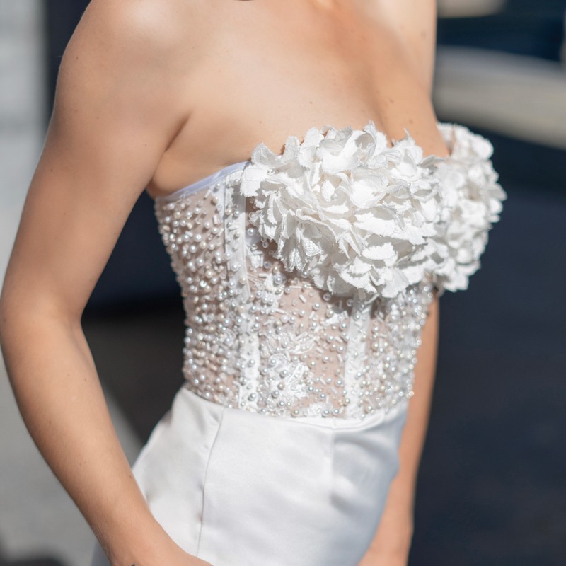 Close-up of hand-embellished pearls, crystals, and flowers on wedding dress bodice