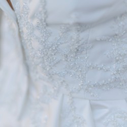 Détails brodés à la main sur veste de mariée en satin duchesse de luxe