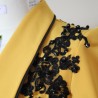 Close-up of black lace and bead detailing on mustard evening jacket Close-up of black lace and bead detailing on mustard evening jacket